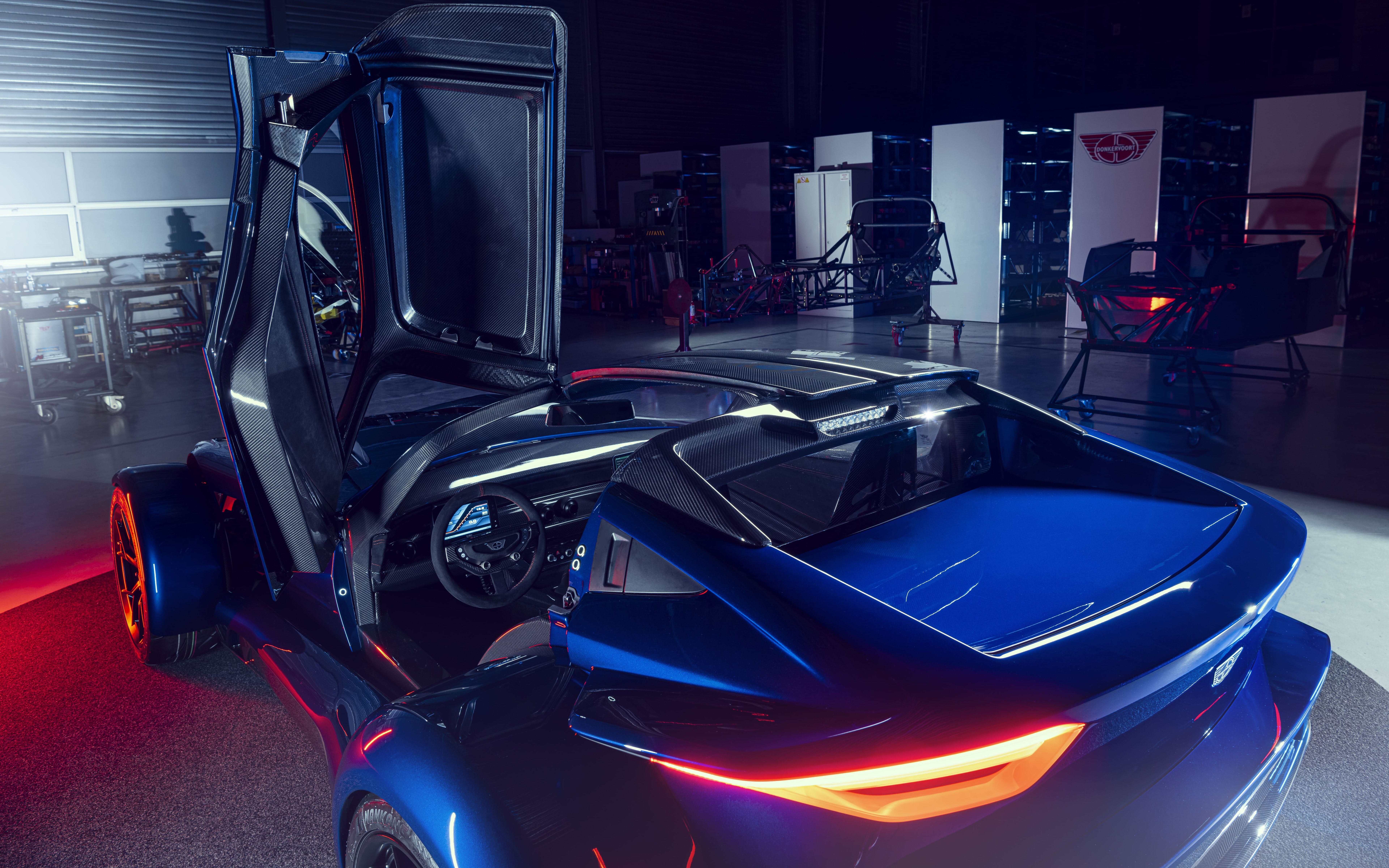 Şık, metalik gümüş rengi bir spor otomobil, karanlık bir zemin üzerinde yumuşak stüdyo ışıklarını yansıtıyor.